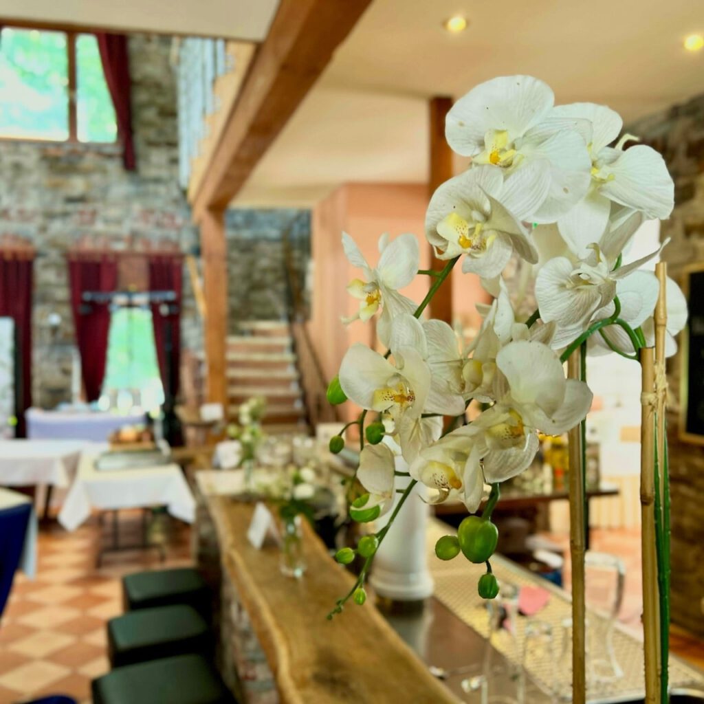 Weiße Orchideen-Deko an der Bar im Landhaus Grum, im Hintergrund der DJ-Stand für die Hochzeit von Janina und Daniel.