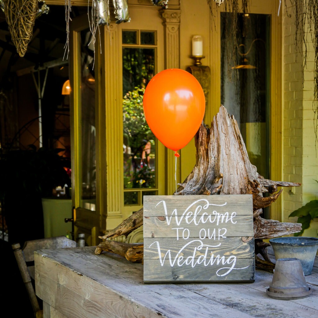 Hochzeit im Erk’s Café, Schortens – Dekoration mit Holzschild „Welcome to our Wedding“ und orangem Ballon als herzliche Begrüßung der Gäste.
