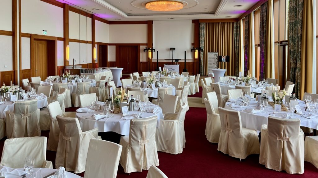 Elegant gedeckte runde und lange Tische mit weißen Hussen im Festsaal des Atlantic Hotels Wilhelmshaven
