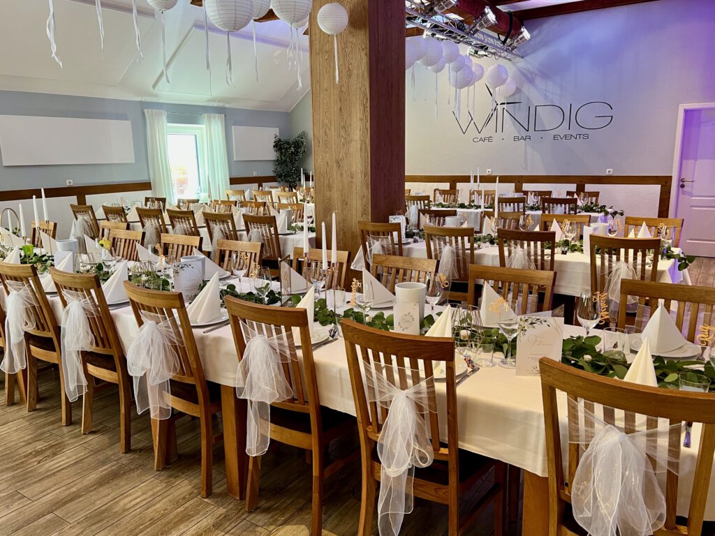 Festlich dekorierter Hochzeitssaal im Windig Steinhausen mit weißen Stuhlhussen, Tischdeko und eleganter Atmosphäre.
