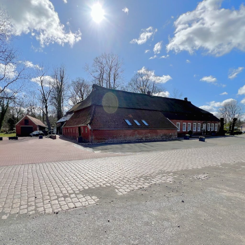 Außenansicht des Sandhorster Krugs in Aurich mit Backsteingebäude und Reetdach