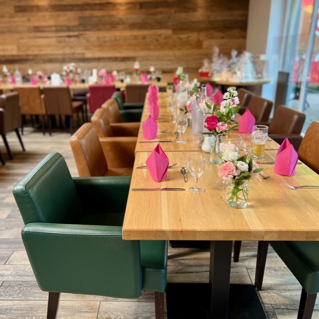 Hochzeitstafel im Seehuus Falkensteinsee Festlich gedeckter Tisch mit pinken Servietten und Blumenschmuck bei der Hochzeit von Kathrin & Georg