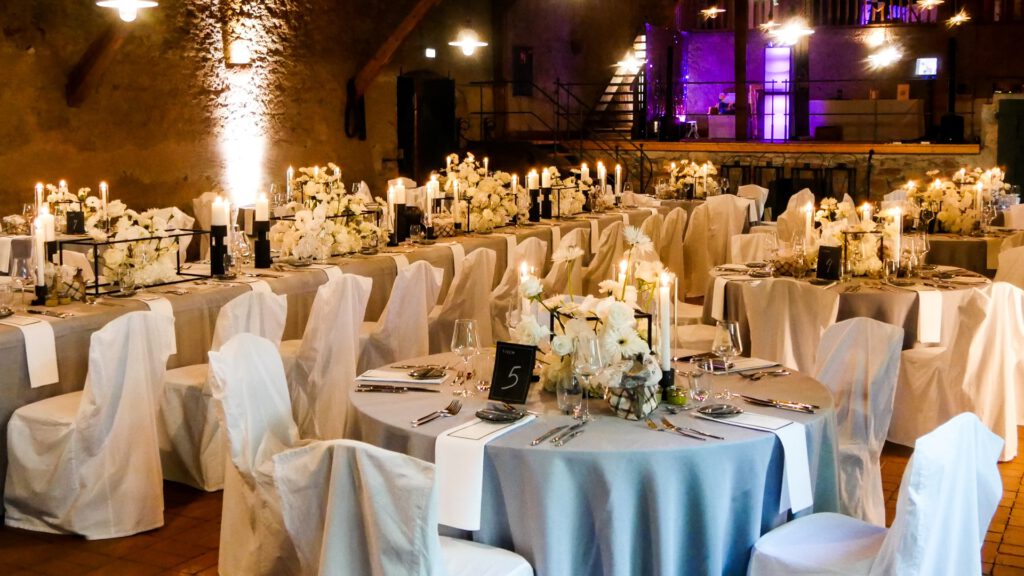 Festlich gedeckte Tische im Hofgut von Hünersdorff, mit weißen Stuhlhussen, eleganter Blumendekoration in Weiß und Kerzenlicht, aufgenommen bei einer Hochzeitsfeier am 10.09.2022.
