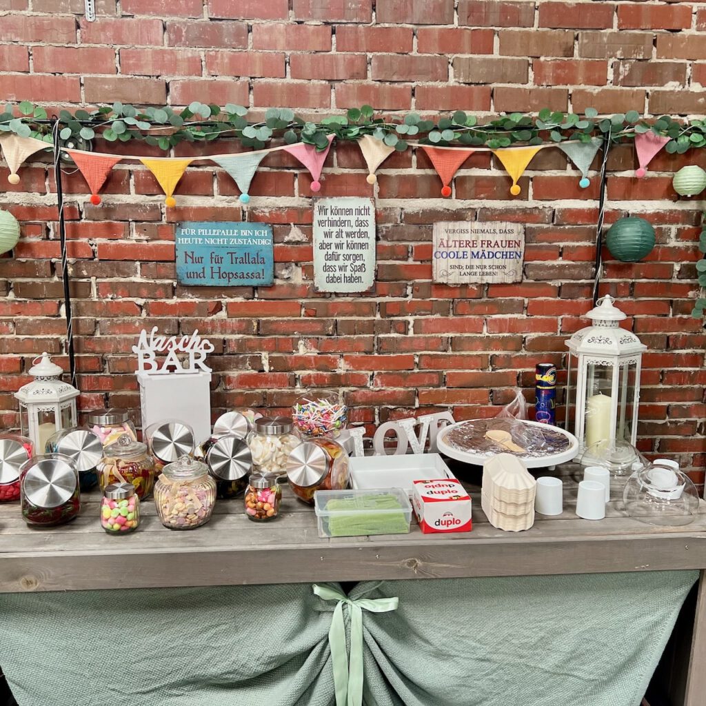 Candybar mit bunten Süßigkeiten und humorvollen Schildern für das Triple-Jubiläum