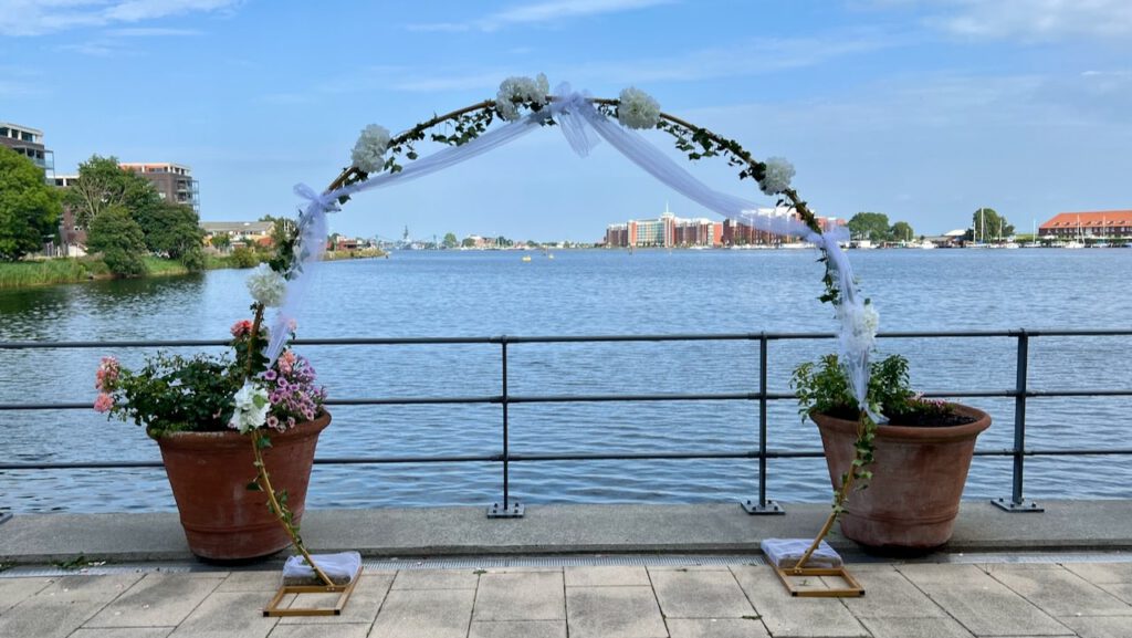 Traubogen mit Blumen und Schleierdeko am Wasser beim ATLANTIC Hotel Wilhelmshaven