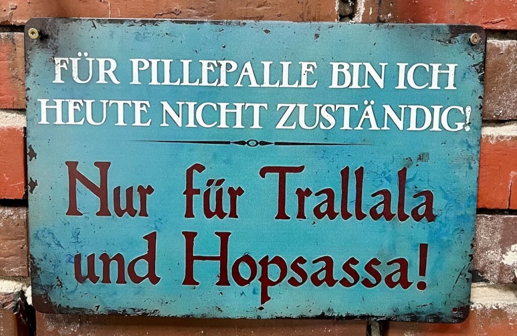 Metallschild mit dem Spruch „Für Pillepalle bin ich heute nicht zuständig – nur für Trallala und Hopsassa!“ als Symbol für Spaß und Hochzeitsaufgaben