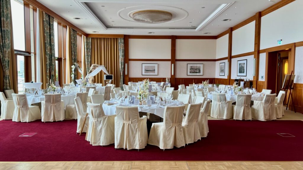 Festlich eingedeckter Hochzeitssaal mit runden Tischen und weißer Stuhlhusse im ATLANTIC Hotel Wilhelmshaven