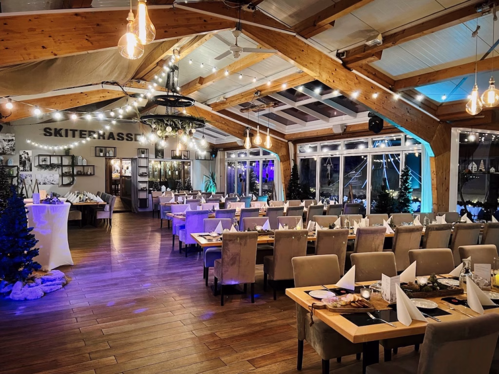 Festlich dekorierter Raum der Skiterrassen in Hooksiel mit Ausblick auf die beleuchtete Terrasse bei Nacht