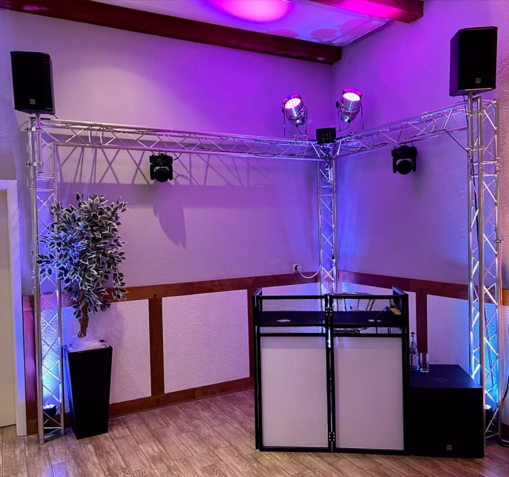 DJ-Pult mit fest installierter Lichtanlage und Traversensystem im Windig Steinhausen – lila Ambiente-Beleuchtung bei einer Hochzeitsfeier