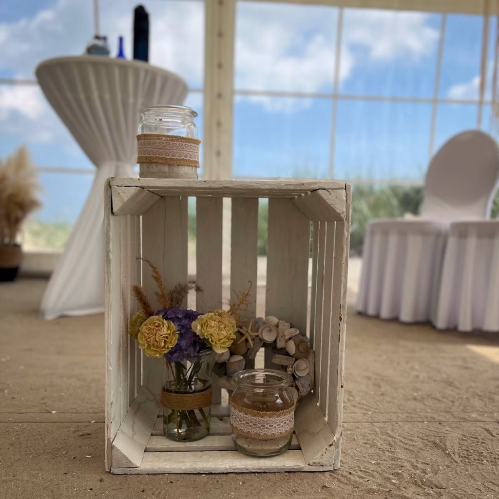 Rustikale Küstendekoration im Trauungszelt Schillig – weiße Holzkiste mit Muscheln, Seesternen und Wildblumen