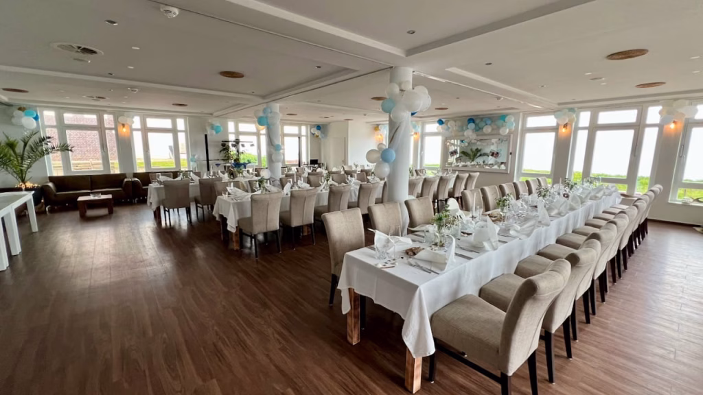 Festlich gedeckter Saal im Restaurant Krüsch auf Wangerooge mit Meerblick und blau-weißer Ballondekoration
