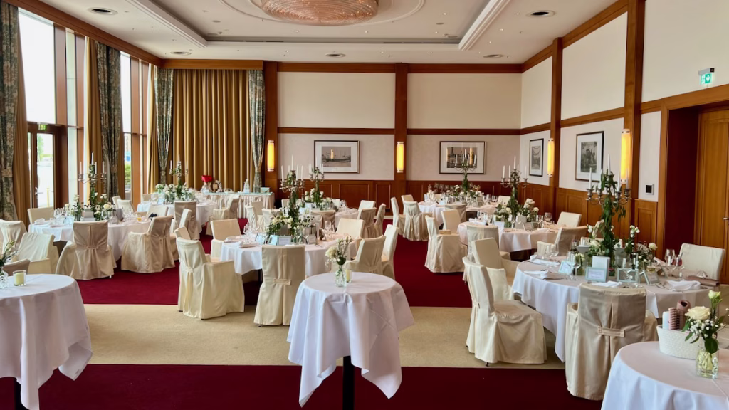 Festlich eingedeckter Ballsaal im ATLANTIC Hotel Wilhelmshaven mit Kerzenleuchtern und rotem Teppich bei einer Hochzeitsfeier