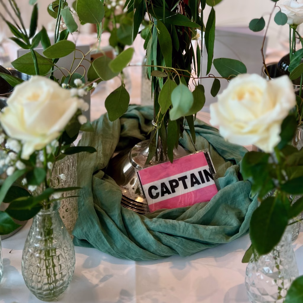 Kapitänsbinde auf festlich dekoriertem Hochzeitstisch mit weißen Rosen, Eukalyptus und Silbervase im ATLANTIC Hotel Wilhelmshaven