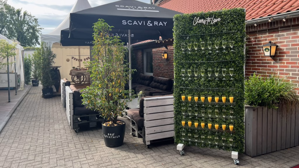 Außenbereich des Windig Steinhausen mit Loungemöbeln, Scavi & Ray Stand und dekorativer Gläserwand beim Hochzeitsempfang