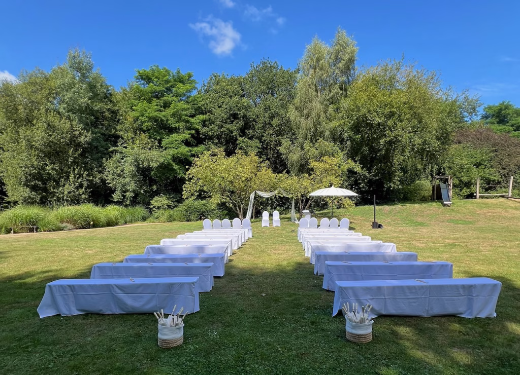 Aufgebaute Sitzreihen für eine freie Trauung im Garten der Wassermühle Wardenburg unter blauem Himmel