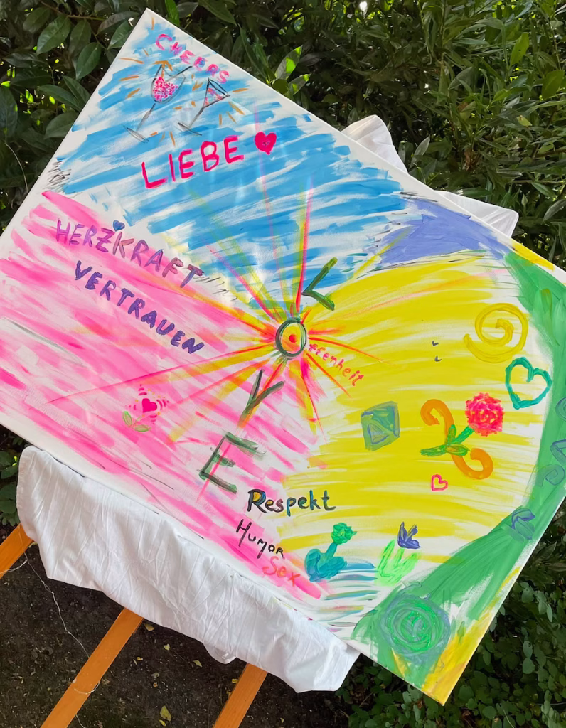 Bunte, gemeinsam von Hochzeitsgästen bemalte Leinwand mit den Worten Liebe, Vertrauen, Respekt als Gästebuch-Alternative