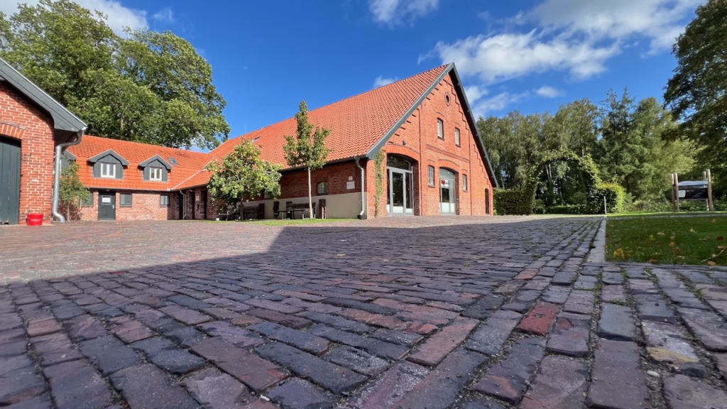 Außenansicht des Jasperhofs in Westerstede – roter Backsteinbau mit Kopfsteinpflaster und blauem Himmel bei einer Hochzeitsfeier